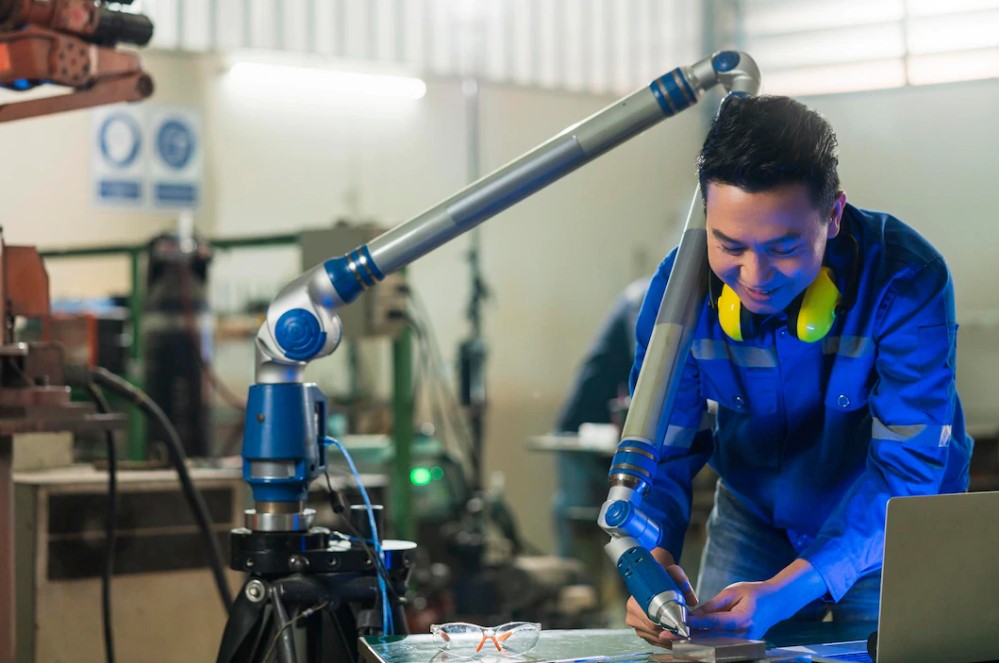 Engineer working in factory with manufacturing robots